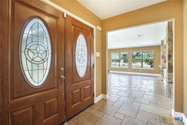 foyer entrance featuring visible vents, baseboards, and stone tile flooring