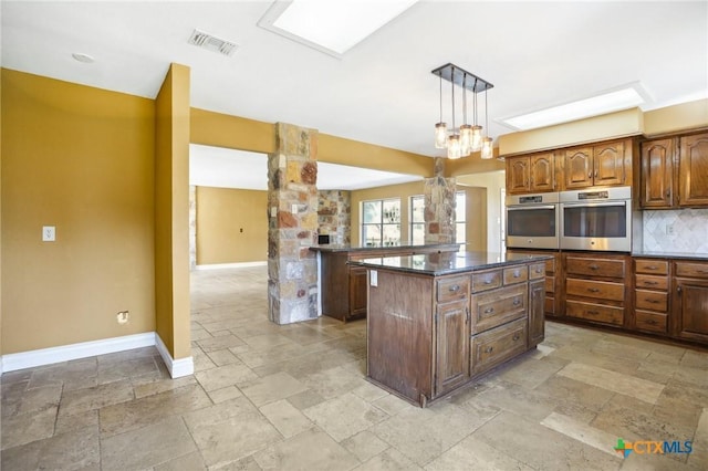 kitchen with dark countertops, oven, stone tile floors, and visible vents