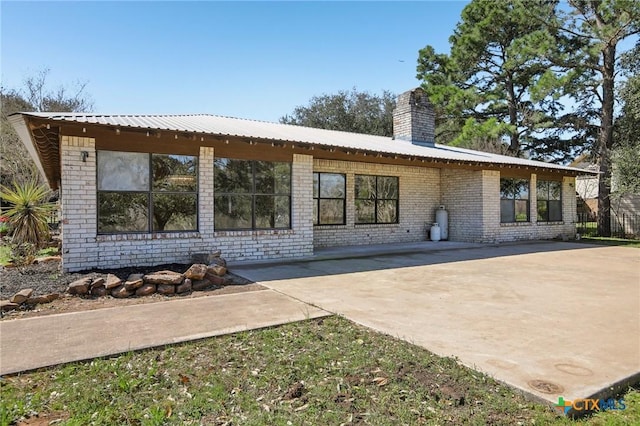 rear view of property with a chimney, brick siding, and a patio