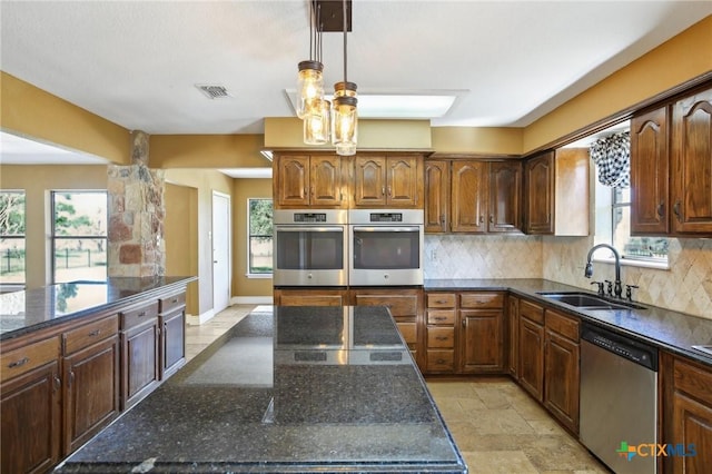 kitchen featuring stainless steel appliances, a sink, dark stone counters, visible vents, and decorative backsplash