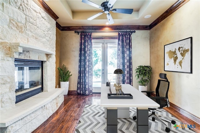 office space featuring a fireplace, ceiling fan, a raised ceiling, and dark wood-type flooring