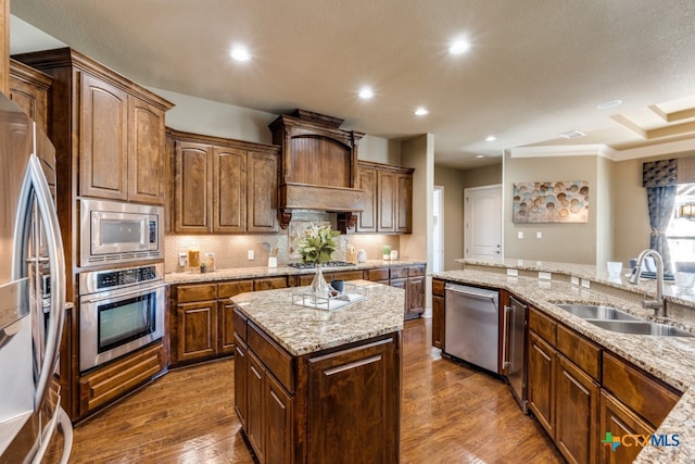 kitchen with a center island, sink, stainless steel appliances, light stone counters, and dark hardwood / wood-style flooring