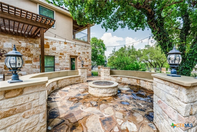 view of patio / terrace with a fire pit, a balcony, and a pergola