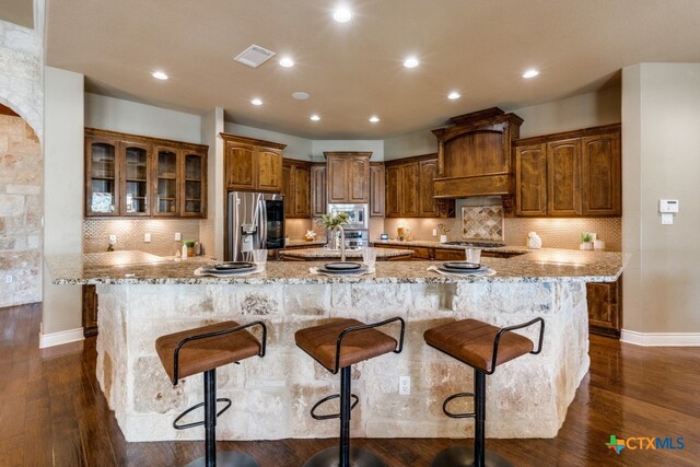 kitchen with a breakfast bar, a large island, dark wood-type flooring, and appliances with stainless steel finishes