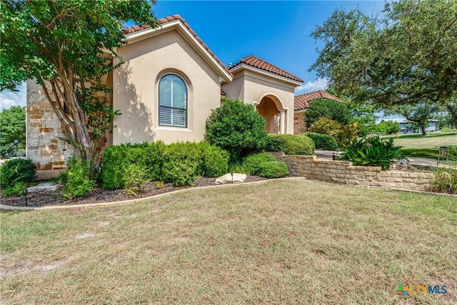 mediterranean / spanish-style home featuring a front yard