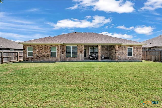 rear view of property with brick siding, a patio, and a fenced backyard