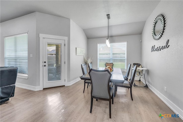 dining space with lofted ceiling, baseboards, and wood finished floors