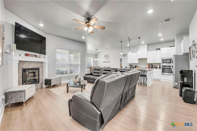 living room featuring a fireplace, recessed lighting, visible vents, light wood-style floors, and a ceiling fan