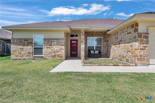 property entrance with stone siding, roof with shingles, and a yard