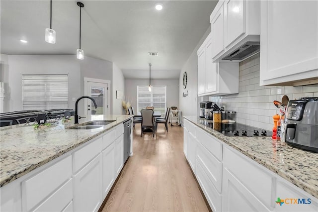 kitchen featuring dishwasher, black electric stovetop, light wood-style floors, white cabinetry, and a sink