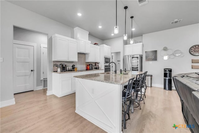 kitchen with stainless steel appliances, light wood-style floors, visible vents, and a sink