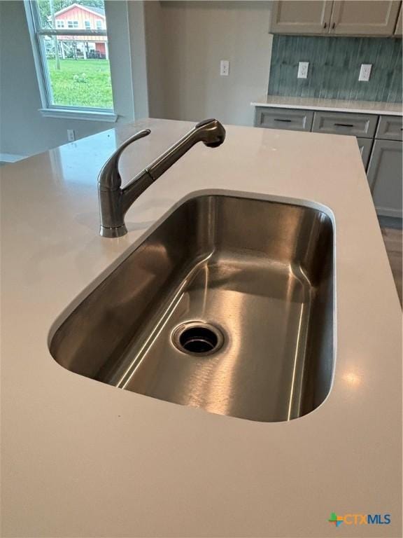 837 Swallow Dr, Palacios, TX 77465 - interior details with gray cabinets, light countertops, a sink, and tasteful backsplash