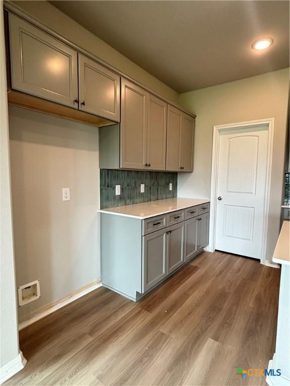 837 Swallow Dr, Palacios, TX 77465 - kitchen featuring light countertops, backsplash, light wood-style flooring, and gray cabinetry