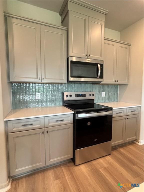 837 Swallow Dr, Palacios, TX 77465 - kitchen featuring backsplash, appliances with stainless steel finishes, light countertops, and light wood-type flooring