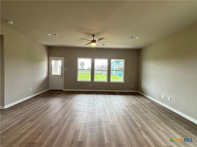 837 Swallow Dr, Palacios, TX 77465 - unfurnished living room with wood finished floors, baseboards, and ceiling fan