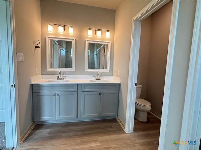 837 Swallow Dr, Palacios, TX 77465 - bathroom with toilet, wood finished floors, a sink, and double vanity