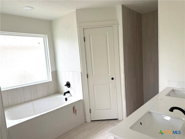 3804 Oglala Trl, Temple, TX 76502 - full bath featuring a bath, wood finished floors, double vanity, and a textured ceiling