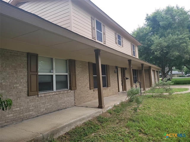 view of side of property with covered porch and a yard