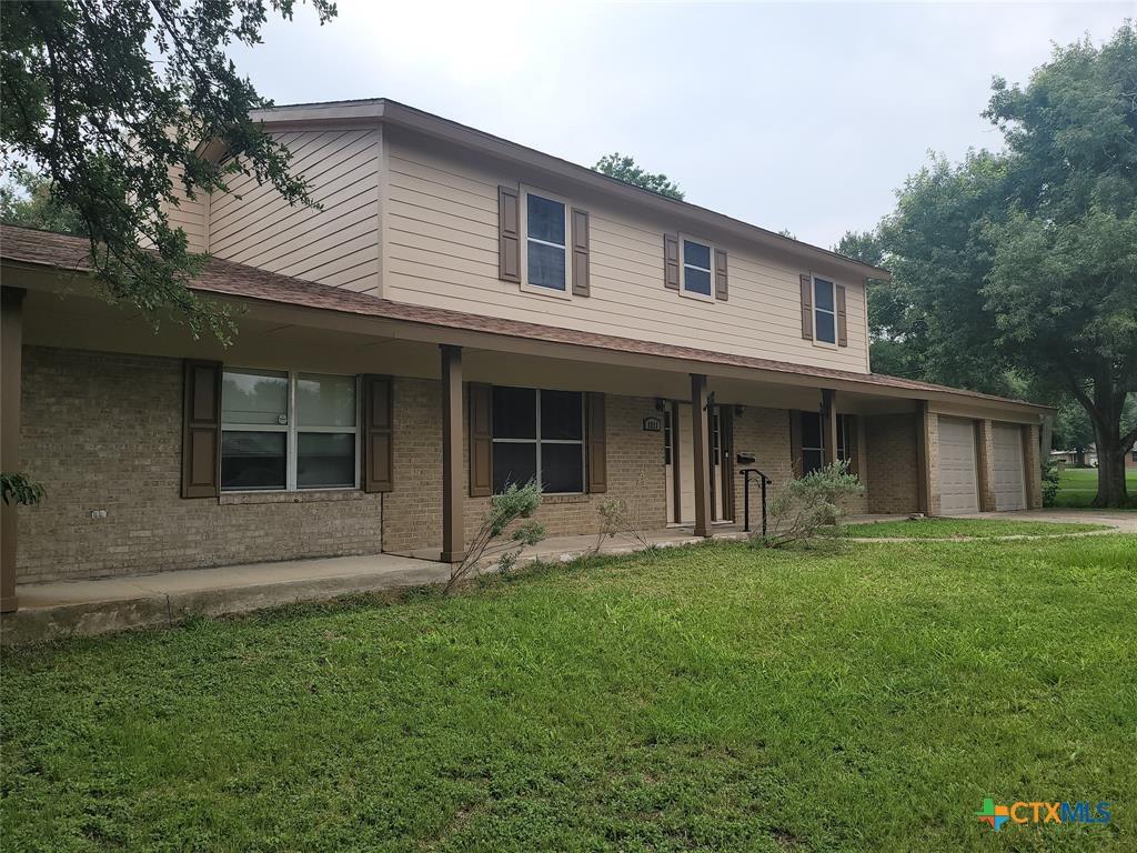 view of front of home featuring a garage, covered porch, and a front lawn