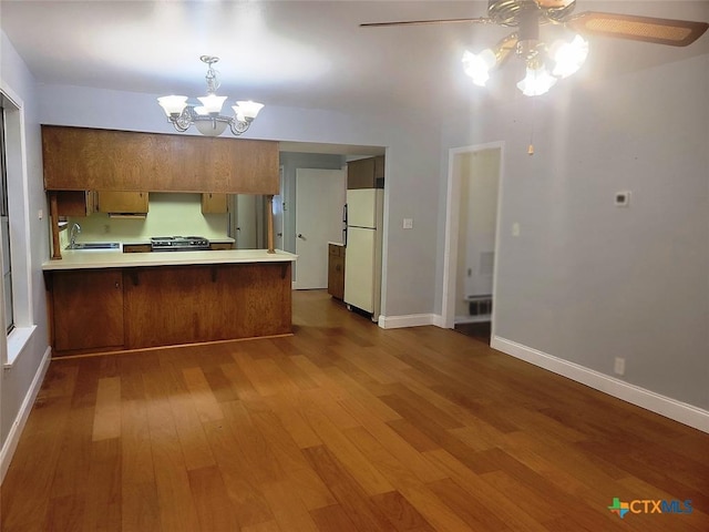 kitchen featuring sink, kitchen peninsula, white fridge, wood-type flooring, and black range with gas cooktop