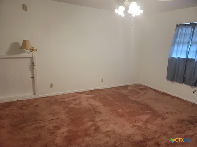 carpeted empty room with a chandelier