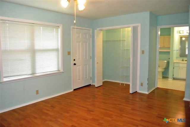 interior space with wood-type flooring, ensuite bathroom, and a closet