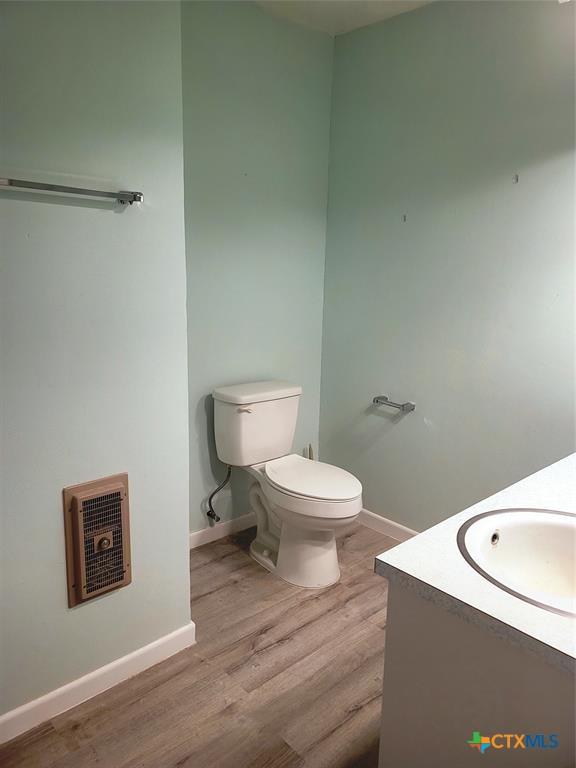 bathroom with hardwood / wood-style floors, vanity, heating unit, and toilet