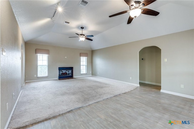 832 Saint James, Seguin, TX 78155 - unfurnished living room featuring light wood-style flooring, ceiling fan, a fireplace with flush hearth, arched walkways, and track lighting