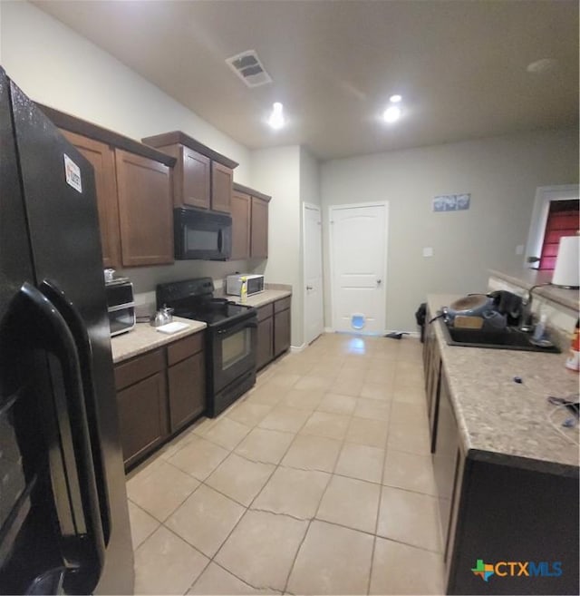 kitchen featuring black appliances, light tile patterned floors, and light countertops
