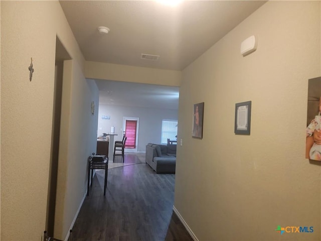 corridor featuring dark wood finished floors and baseboards