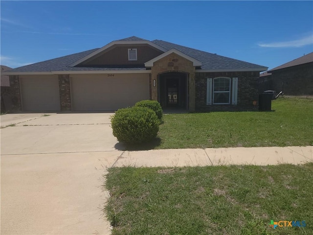 view of front of home featuring an attached garage, driveway, a front yard, and a shingled roof
