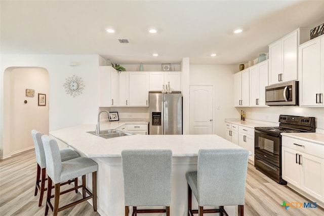 401 Thunder Valley Trl, Georgetown, TX 78626 - kitchen featuring stainless steel appliances, a kitchen breakfast bar, light wood-type flooring, arched walkways, and light countertops