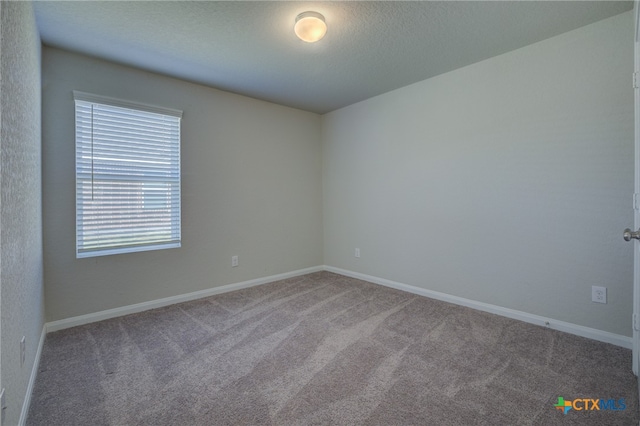 carpeted empty room featuring a textured ceiling