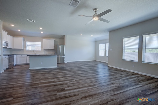 unfurnished living room featuring dark hardwood / wood-style flooring, sink, ceiling fan, and a textured ceiling