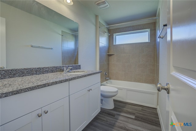 full bathroom with vanity, hardwood / wood-style flooring, tiled shower / bath, and toilet