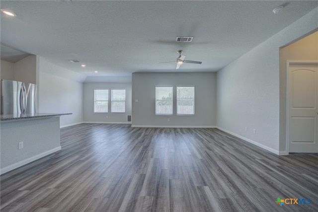 unfurnished living room with dark wood-type flooring, a textured ceiling, and ceiling fan