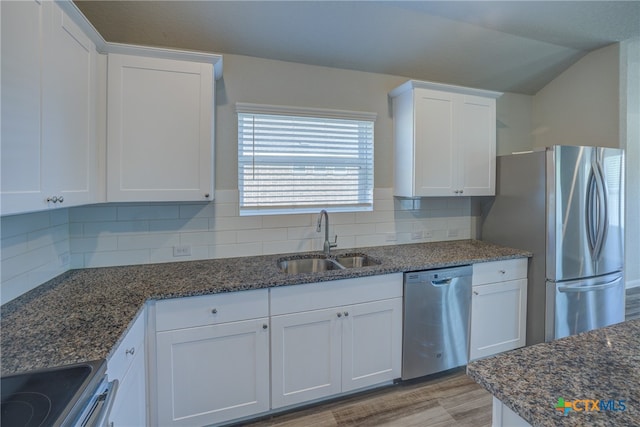 kitchen with dark stone counters, white cabinetry, appliances with stainless steel finishes, and sink