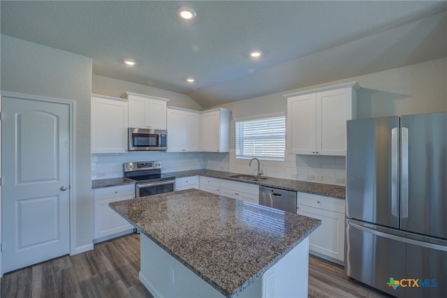 kitchen with white cabinets, appliances with stainless steel finishes, sink, and a center island