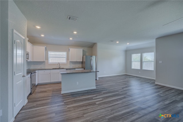 kitchen with stainless steel appliances, wood-type flooring, a center island, white cabinets, and sink