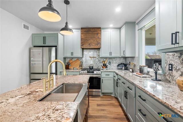 1611 Port Lavaca Dr, Victoria, TX 77901 - kitchen with appliances with stainless steel finishes, a sink, tasteful backsplash, pendant lighting, and light stone countertops