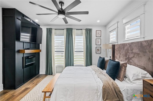 1611 Port Lavaca Dr, Victoria, TX 77901 - bedroom with light wood finished floors, a glass covered fireplace, recessed lighting, and a ceiling fan