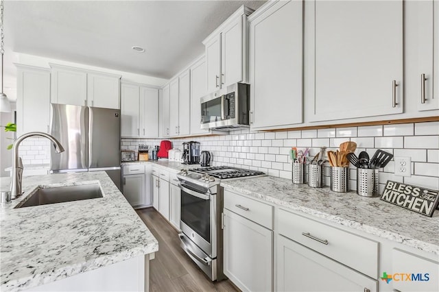 15651 Baronial Castle Dr, Humble, TX 77346 - kitchen featuring appliances with stainless steel finishes, dark wood-type flooring, decorative backsplash, light stone countertops, and white cabinetry