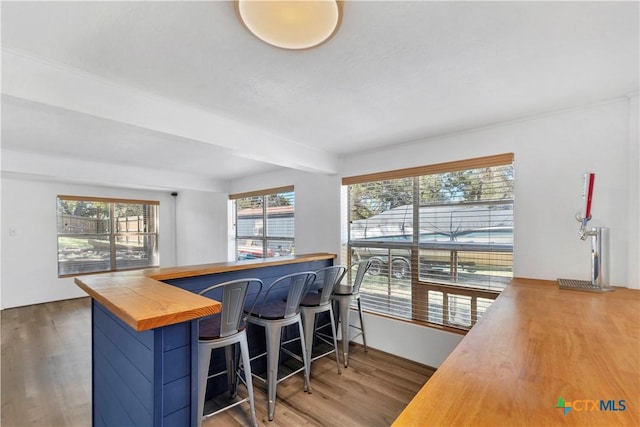 kitchen featuring a kitchen breakfast bar, wooden counters, a peninsula, and wood finished floors