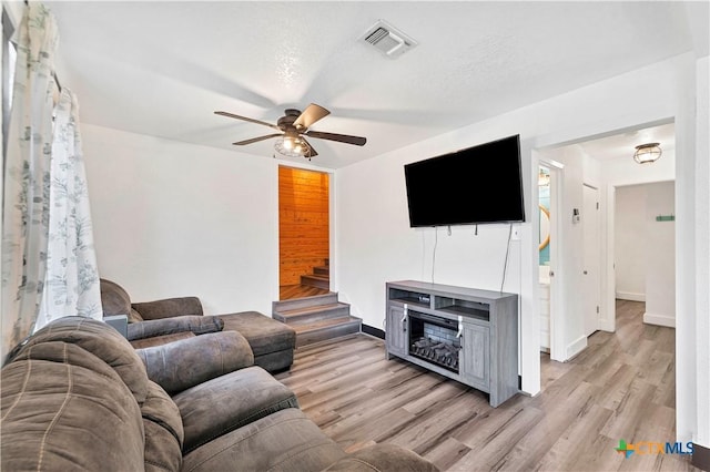 living area with visible vents, baseboards, ceiling fan, stairs, and light wood-style floors