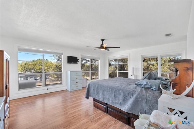 bedroom with access to exterior, visible vents, ceiling fan, light wood-style flooring, and a textured ceiling