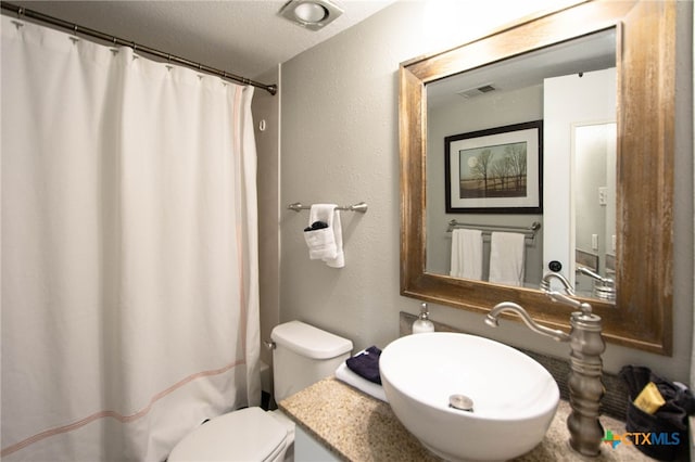 bathroom featuring a shower with curtain, a textured ceiling, toilet, and sink