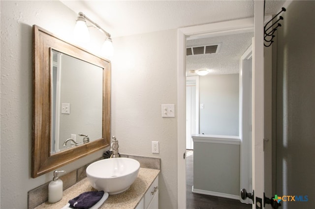 bathroom with vanity, a textured ceiling, and hardwood / wood-style flooring