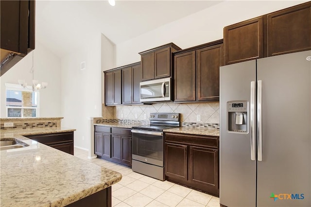 6402 Ambrose Cir, Temple, TX 76502 - kitchen featuring appliances with stainless steel finishes, decorative backsplash, light tile patterned floors, dark brown cabinetry, and light stone counters