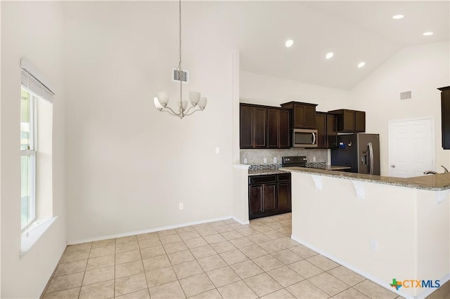 kitchen featuring appliances with stainless steel finishes, a kitchen breakfast bar, decorative backsplash, hanging light fixtures, and an inviting chandelier