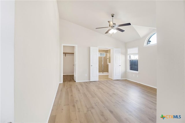 unfurnished bedroom featuring lofted ceiling, a walk in closet, ceiling fan, light hardwood / wood-style floors, and a closet